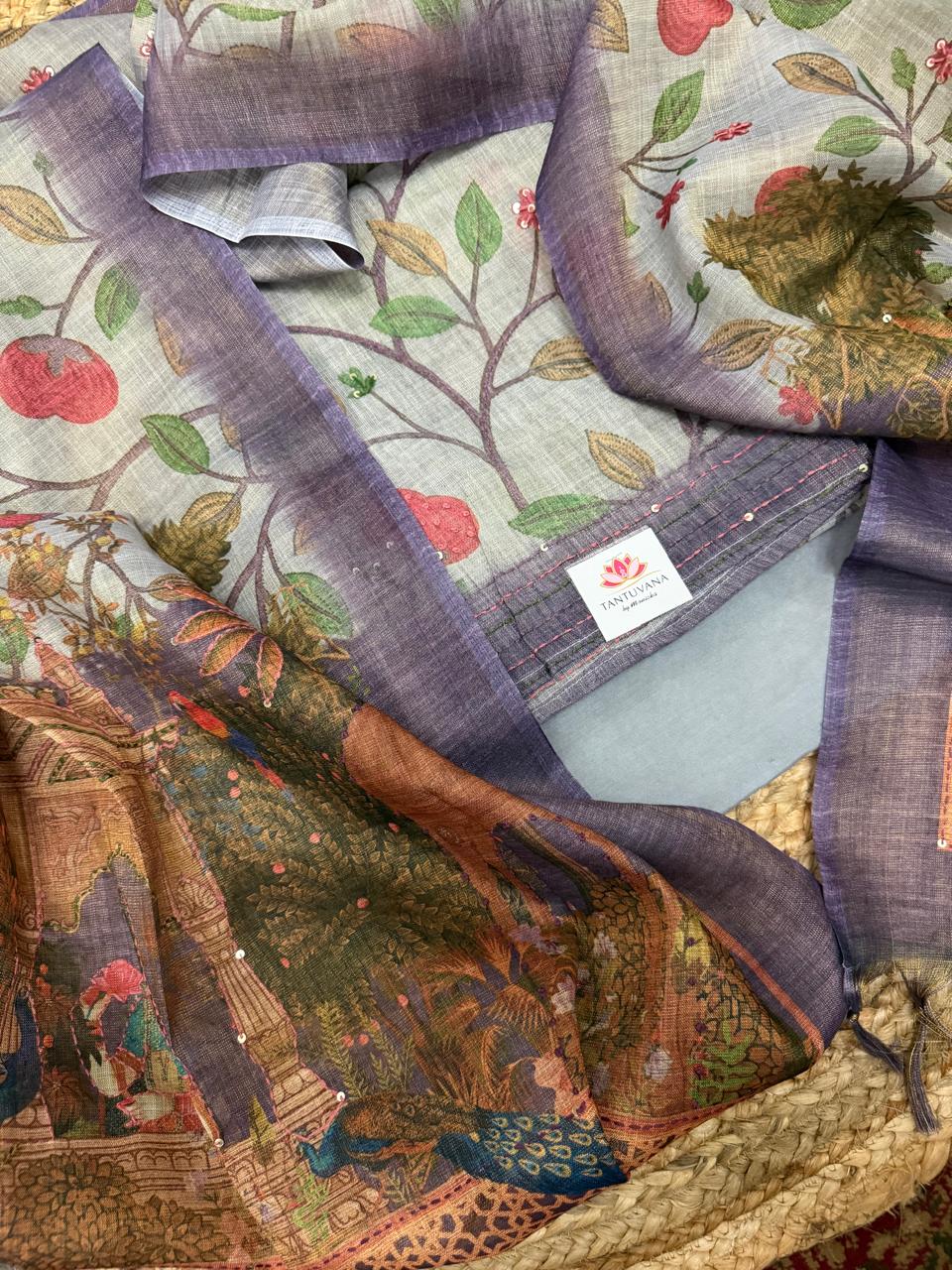 Grey gold Mughal print jute linen 3-piece unstitched suit set – draped flat lay showing all-over pomegranate tree digital print kurta with purple sequin kantha border, Mughal palace scene dupatta, and powder blue bottom fabric