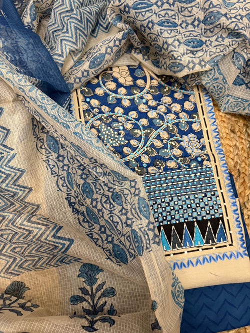 Taupe and blue unstitched suit set – angled flat lay on rattan showing blue floral vine block print neckline panel, Kota Doria dupatta with chevron and floral block print, and taupe kurta fabric