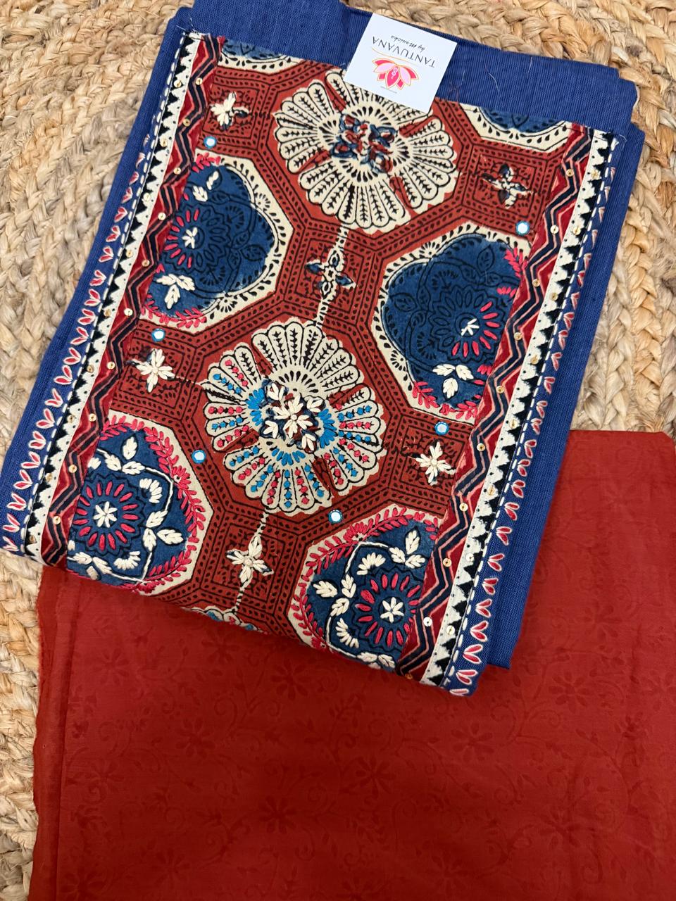 Rust Ajrakh block print neckline panel – close-up of hexagonal lattice with teal and white floral medallions, navy embroidered border