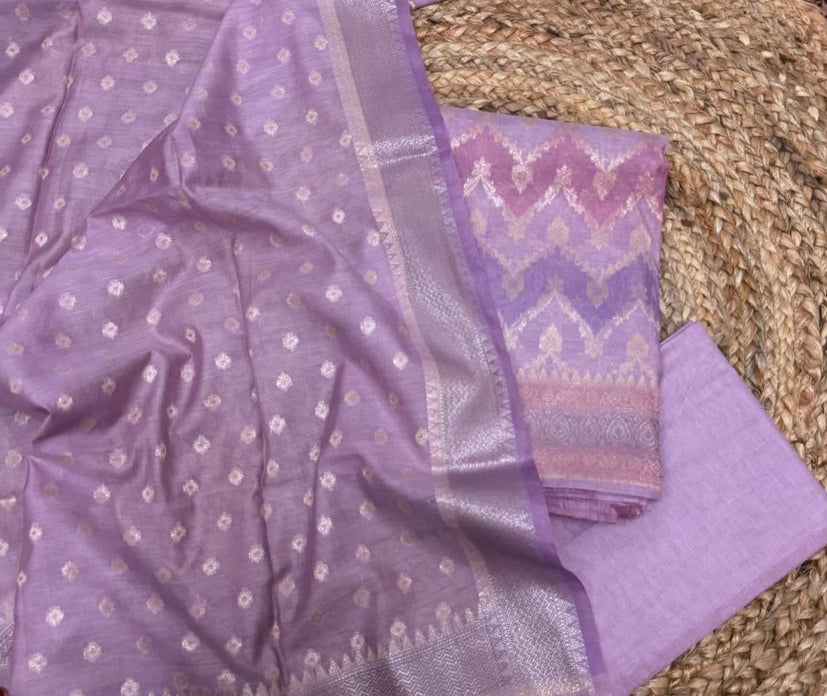 Purple Banarasi Chanderi silk 3-piece unstitched suit set – flat lay on rattan showing purple Chanderi dupatta with silver butti and chevron zari border, pink-purple multi-shade chevron Banarasi woven kurta with silver zari paisley border, and plain lavender cotton bottom