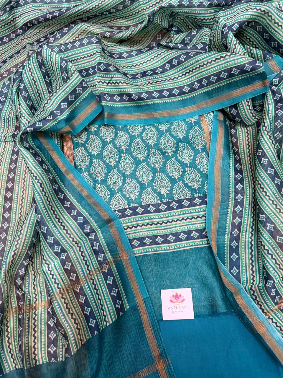 Teal and navy Chanderi silk 3-piece unstitched suit set – draped flat lay showing teal Chanderi kurta with white paisley booti print and navy diamond zigzag border, navy-green geometric stripe dupatta with gold zari selvedge, plain teal Chanderi bottom