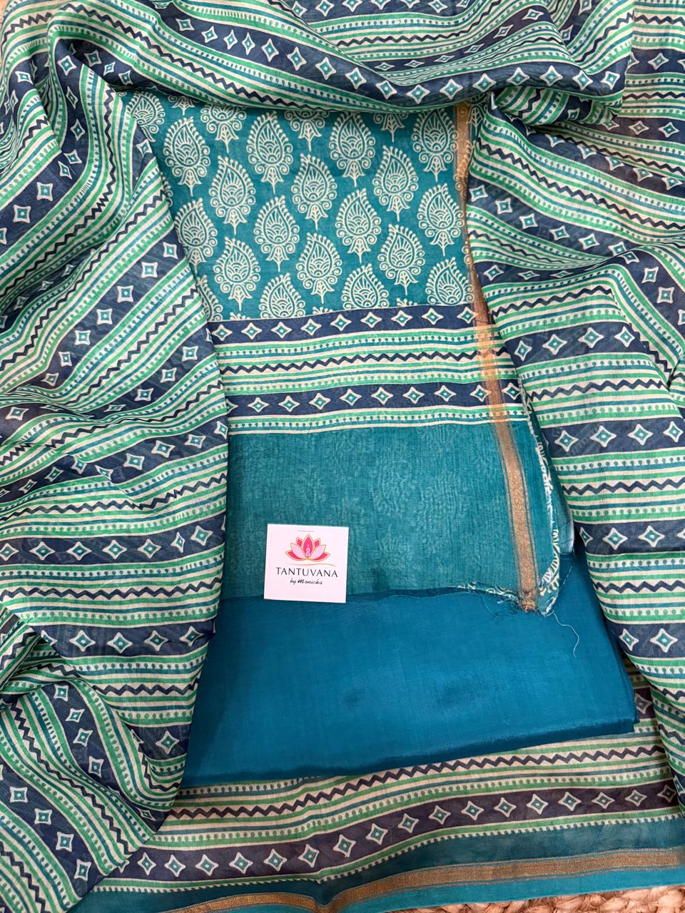 Teal and navy Chanderi silk 3-piece unstitched suit set – overhead flat lay showing teal Chanderi kurta with all-over white paisley booti print, navy diamond zigzag border band, plain teal Chanderi bottom with gold zari edge, surrounded by navy-green geometric stripe dupatta