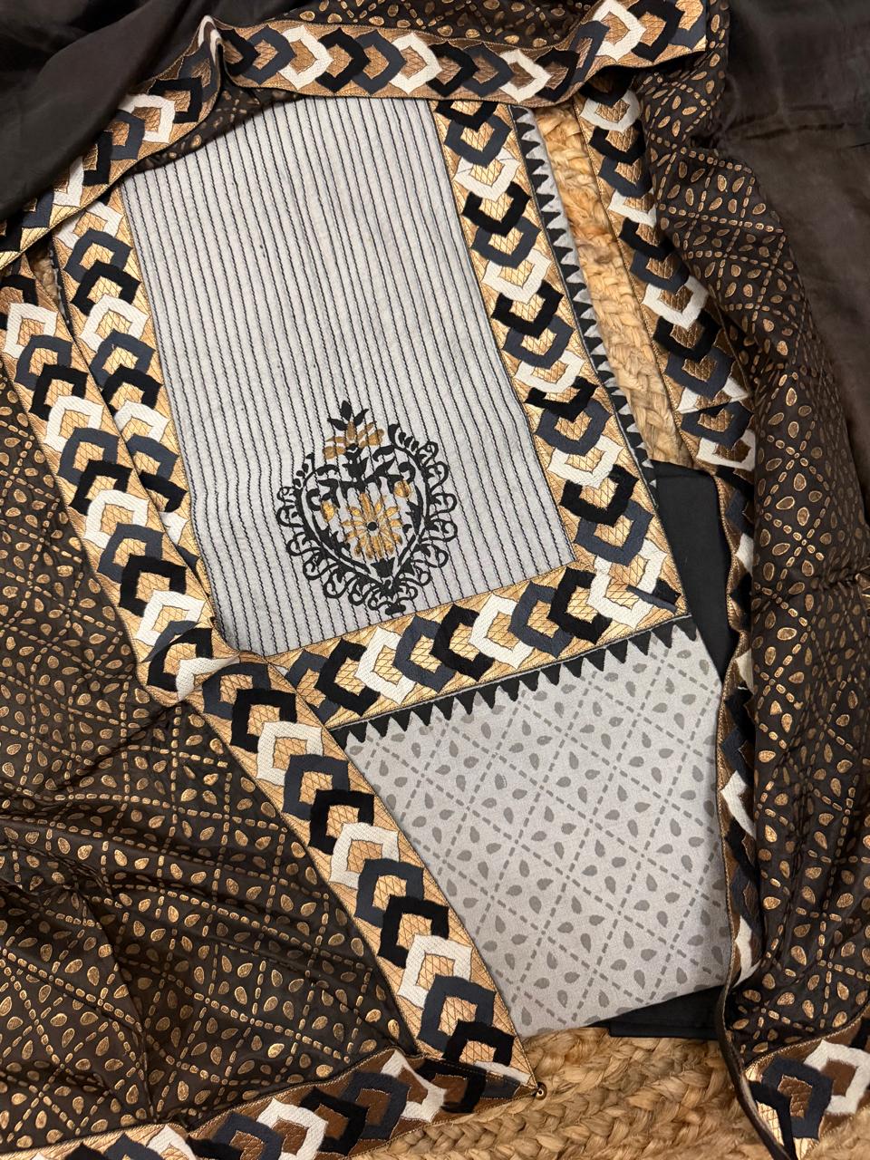 Grey and black cotton silk 3-piece unstitched suit set – angled flat showing grey striped cotton silk kurta with black and gold printed floral medallion, black and gold chevron block print silk dupatta border, and black bottom