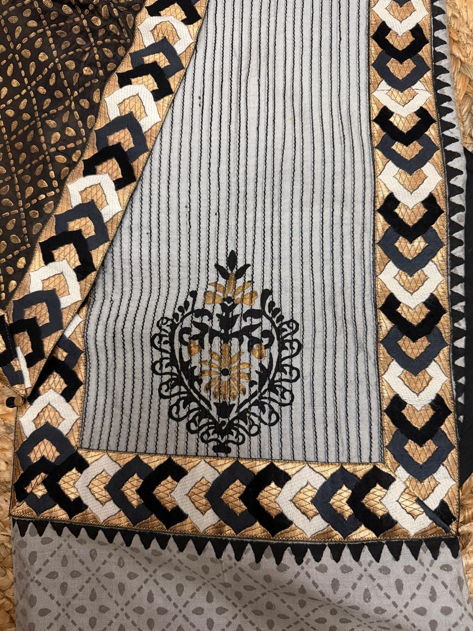 Grey cotton silk kurta fabric – close-up of vertical stripe texture with intricate black and gold floral medallion print at center, black and gold chevron block print border, and scallop zigzag hem detail, framed by grey diamond embroidered border